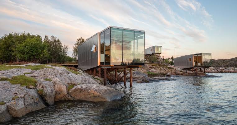 Timber cabin with a glazed end standing on a stone quay above northern Norwegian water