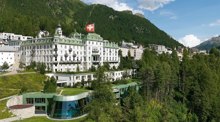 Nineteenth-century hotel facade above a lawn facing an alpine side valley